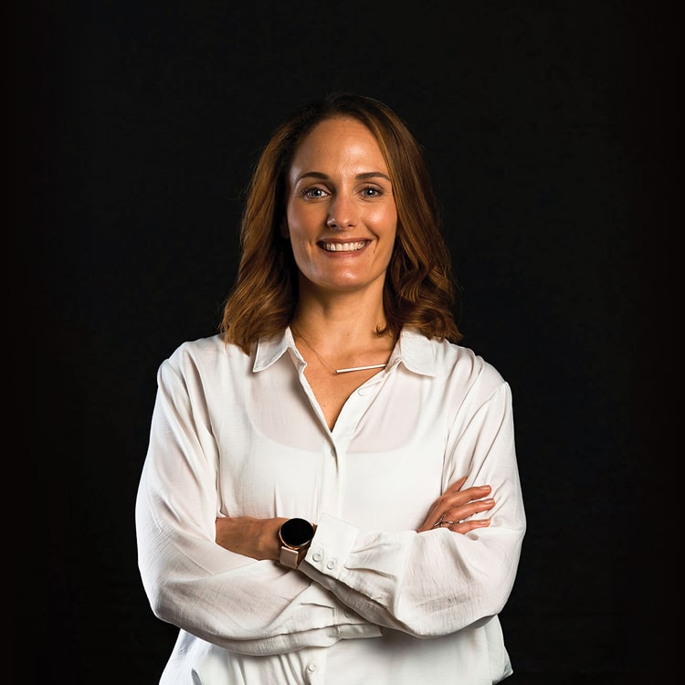 Jade Paddock, Studio Coordinator at Spruik, wearing a white shirt, while smiling and looking into the camera with a black background