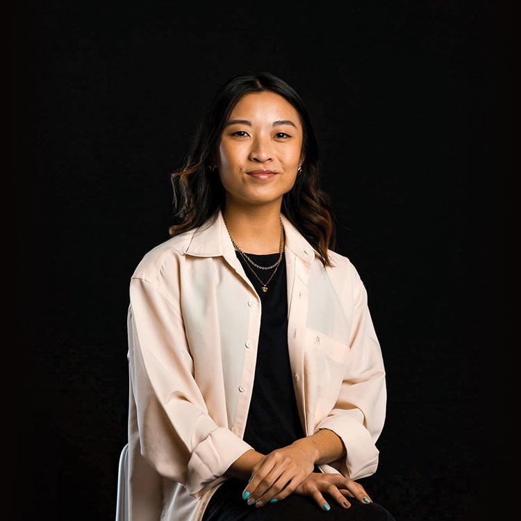 Jessica Lim, Account executive at Spruik, wearing a light pink shirt while smiling and looking at the camera with a black background.